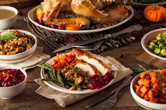 a thanksgiving meal spread of turkey, cranberries, asparagus, carrots and more