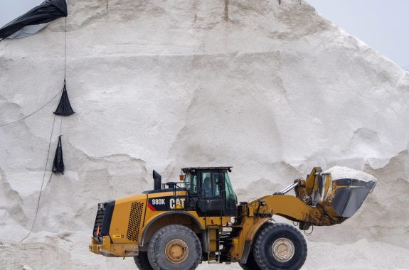 A truck carries salt mined from an enormous salt deposit behind it.