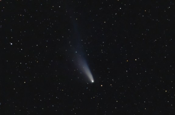 A white comet streaks through a starry night sky.