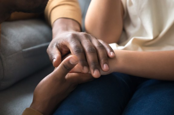 a close up of a black person's hands holding a child's hands