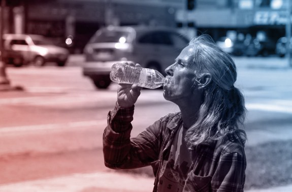 A woman drinking water on the street in Houston