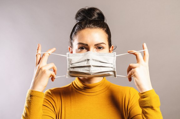 Una mujer poniendo una mascarilla para el COVID 19