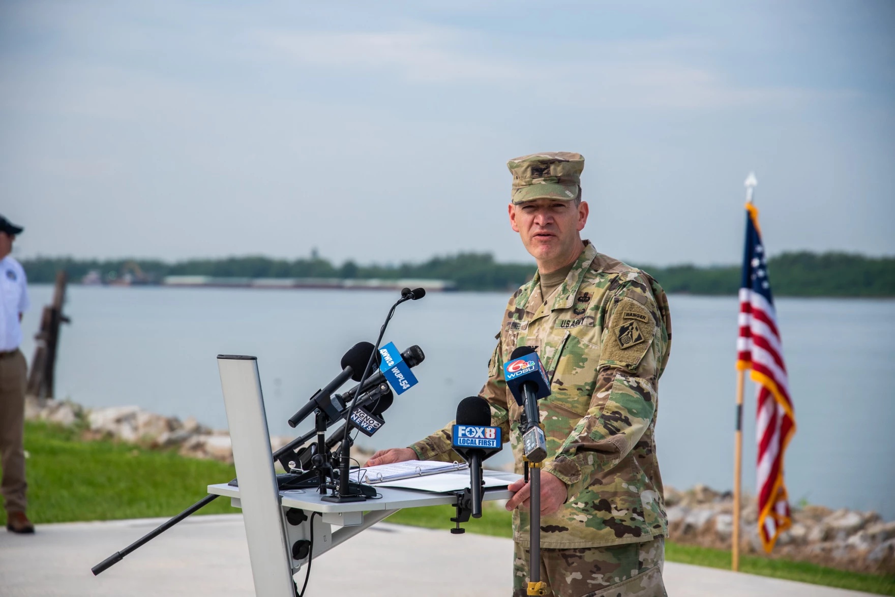 A man in an army uniform speaks at a press conference. Medium shot