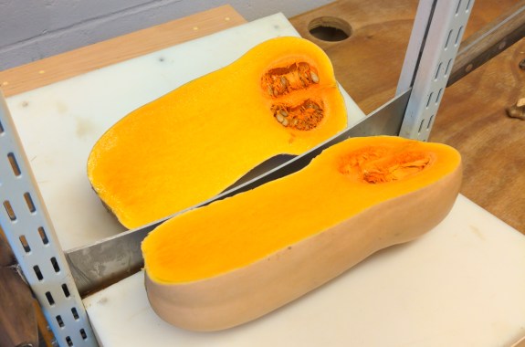 A large orange squash cut right down the middle by a shiny device that looks like a guillotine