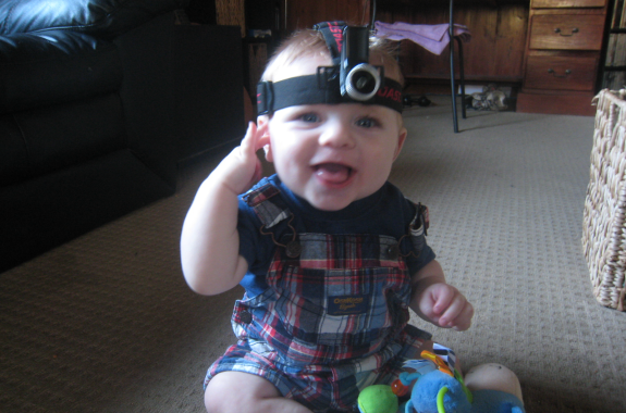 A smiling baby wearing a head camera