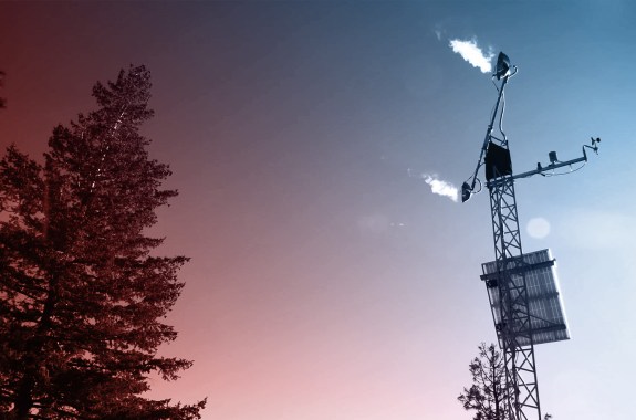 A metal tower with a structure emitting steam on the top.