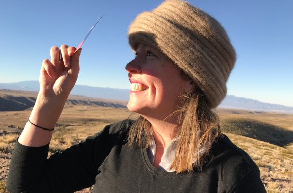 A woman holds a solar viewing filter between her eyes and the sun as she watches an eclipse