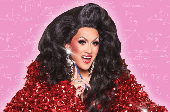 A drag queen wearing a shiny red shirt that looks like it's made of wrapping ribbons. She's smiling at the camera, holding a pencil. Behind her are math equations and formulas.