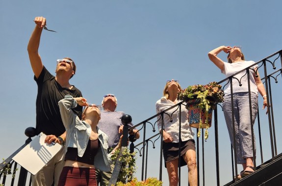 A family wearing eclipse glasses and looking up at the April 8 eclipse.