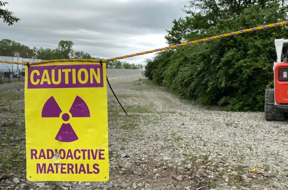 A rope crossing over a dirt road that reads "CAUTION: Radioactive Materials"