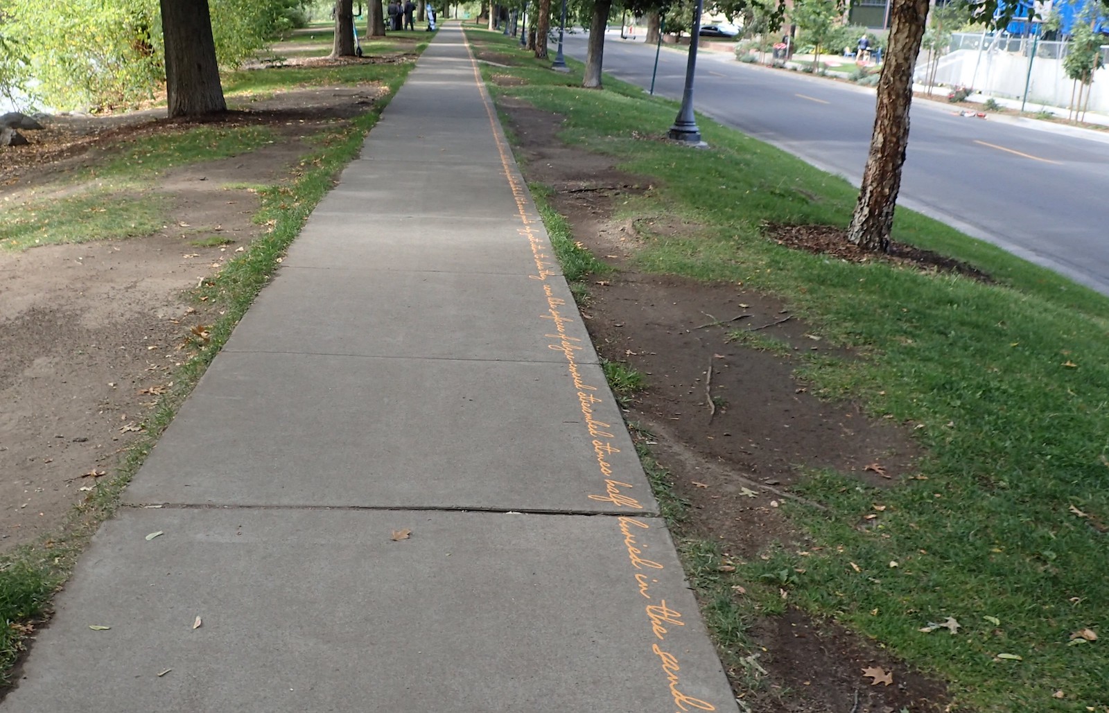 Yellow text written along the curb of a walkway.