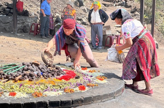 Two people wearing colorful clothing are putting various objects onto a raised circular platform.