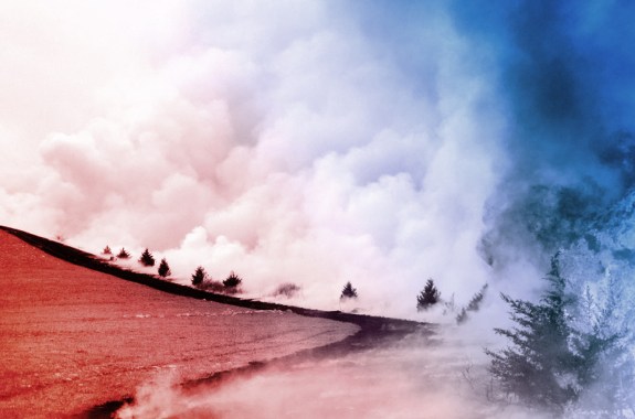 Fire spreading across a grassland, burning trees on its periphery