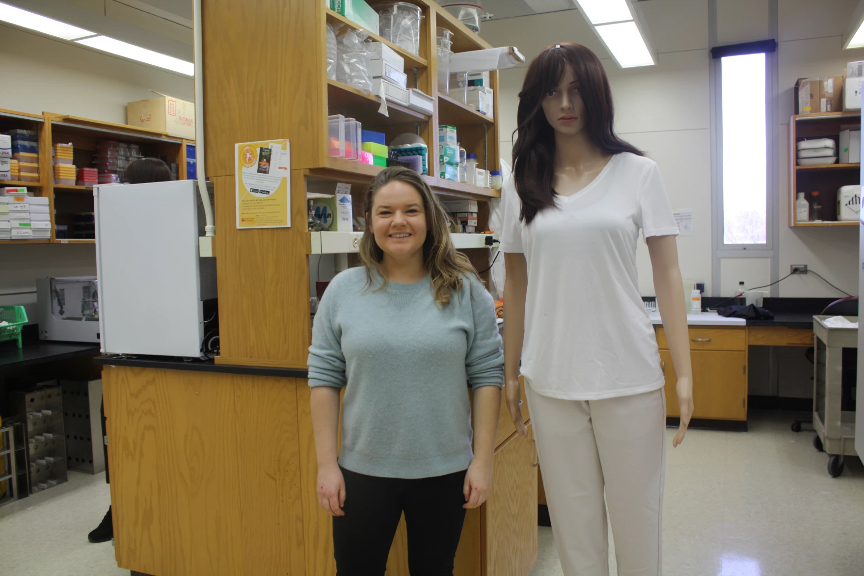 The mannequin stands next to a blond woman. It stands about a foot and a half taller than her.