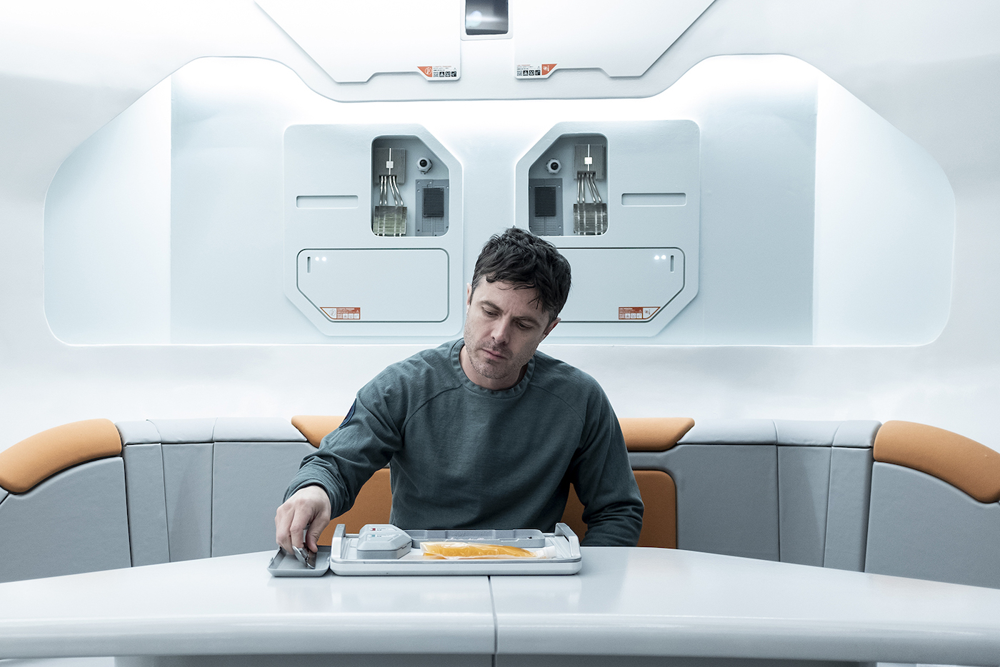 A man inside a space dining area having a pouch of food on a tray.