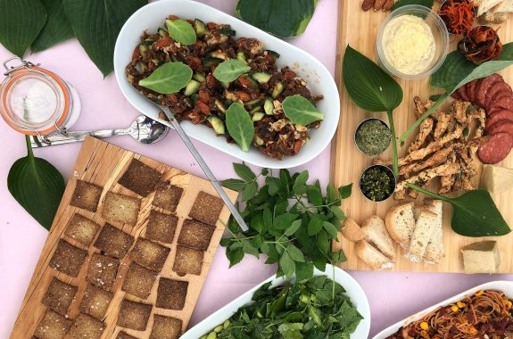 Looking down at a tabletop with trays of various foods.