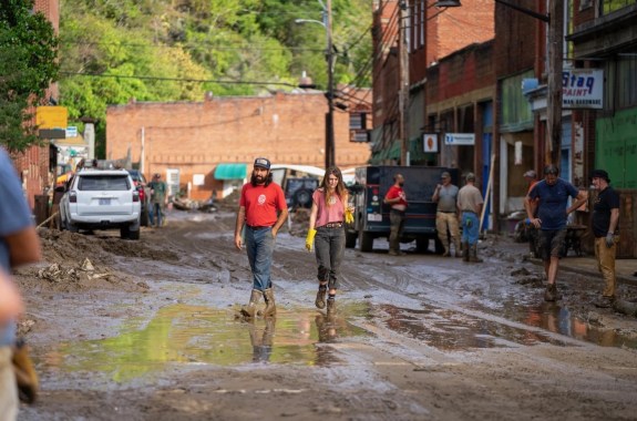 Two people walking through a ruined muddy road