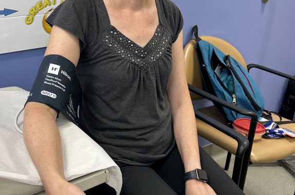 A woman's arm with a blood pressure monitor around it.