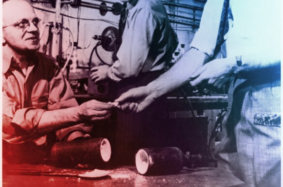 A few people passing items between their hands. On the table in front of them is a capsule filled with spilling white powder