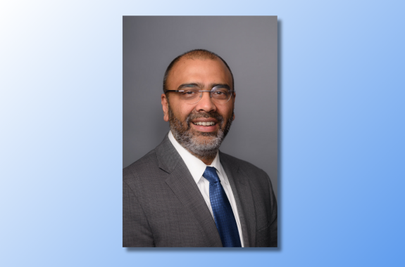A man wearing glasses smiling for a headshot