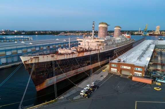 A large ship with signs of weathering sits in a dock.