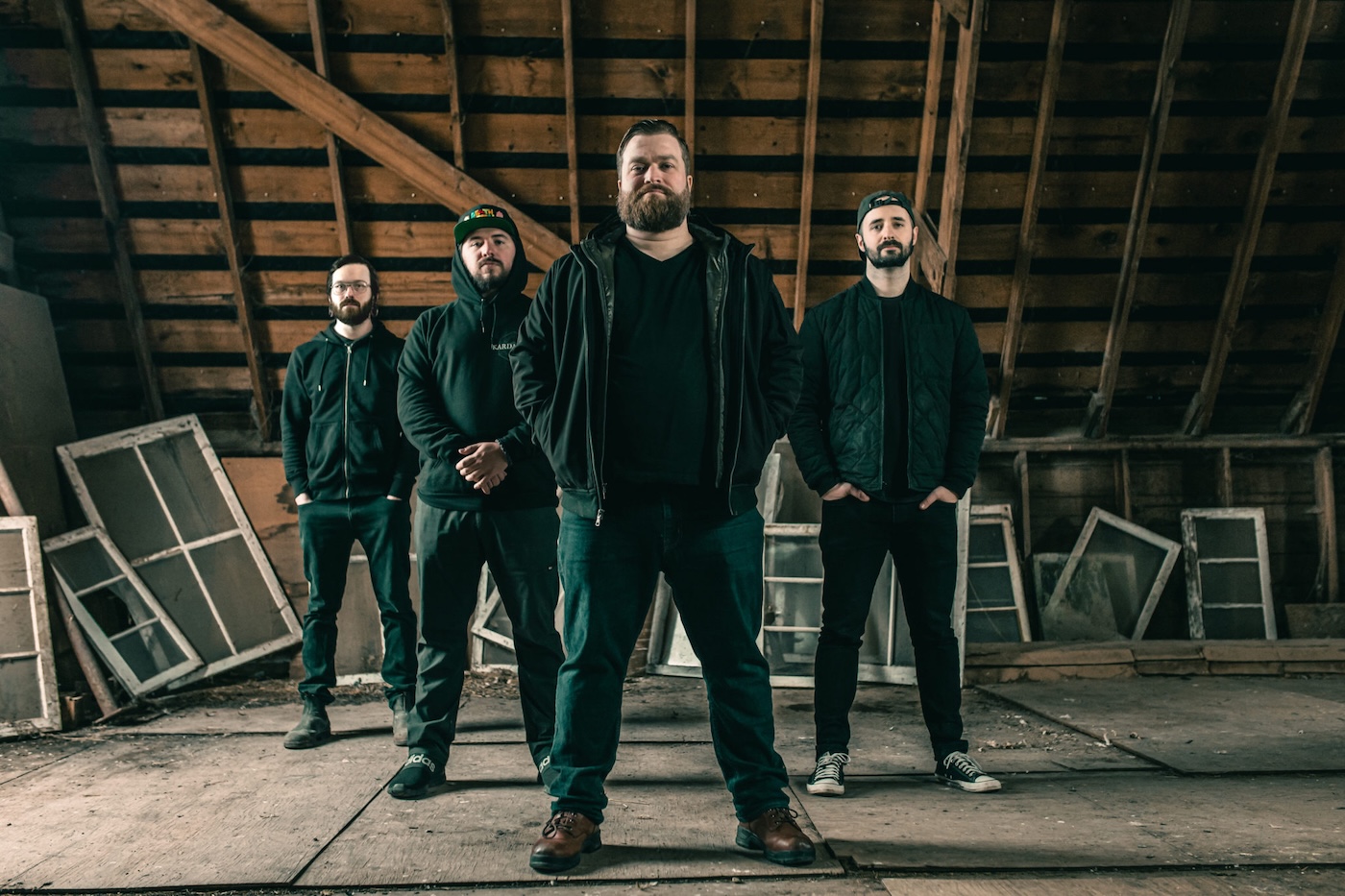Four men stand tall in a dusty large attic