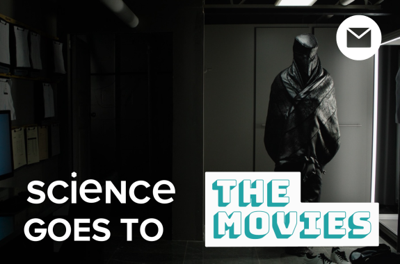 A person standing wearing a full body coverage grey fabric wrap that covers his face.