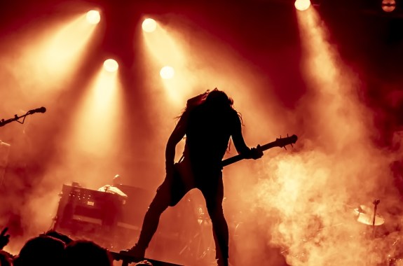 silhouette of guitar player in action on stage in front of concert crowd