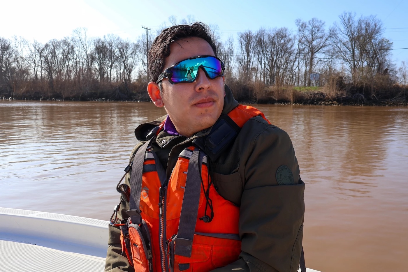 A man wearing sunglasses on a boat floating on brown water