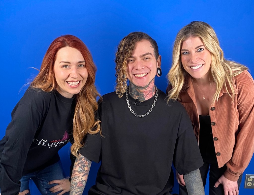 Three people sitting next to one another, smiling at the camera