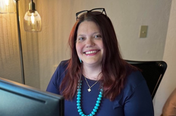 A woman sitting at a desk smiling at the camera