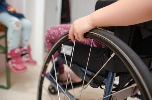 close-up hand of a child on a wheel from a wheelchair.