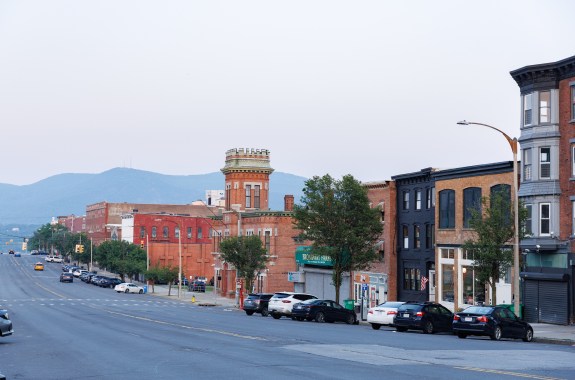 Edificios de ladrillo a lo largo de una calle ancho con montañas al fondo.