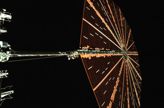 A wide hexagon shaped wing of a spacecraft in space.