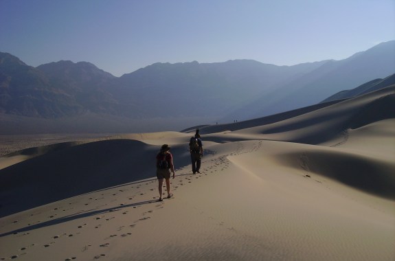 Two people walking on sand dunes