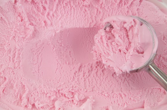 Metallic ice-cream scoop with strawberry ice cream close up