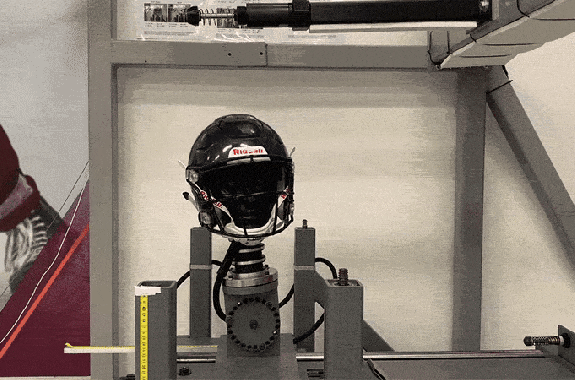 A big pendulum swings and hits a helmet on a dummy head. Concussion, sports injury testing
