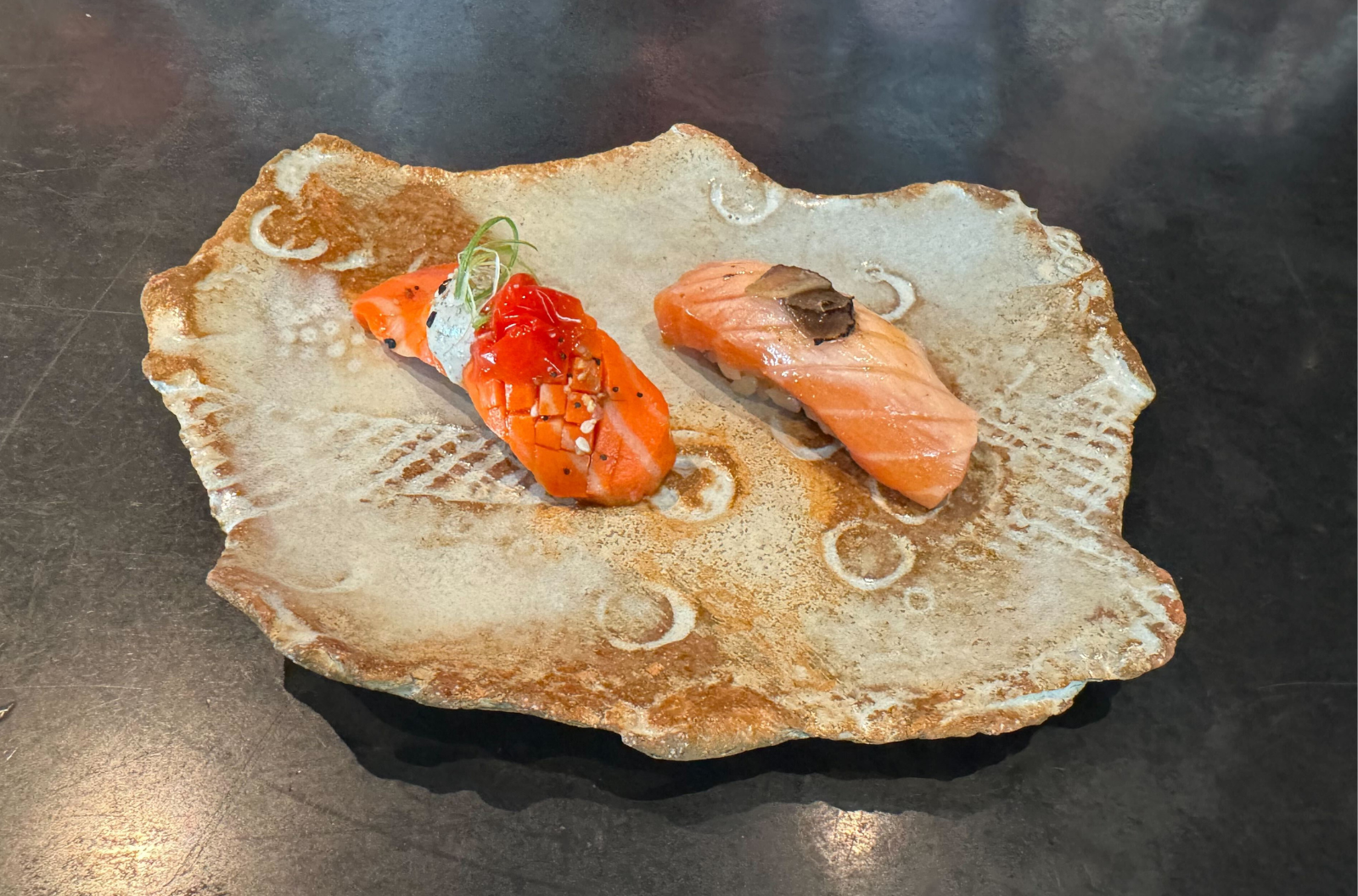 two pieces of salmon sushi, the one on the left is cultivated salmon in a lab. wildtype lab grown meat