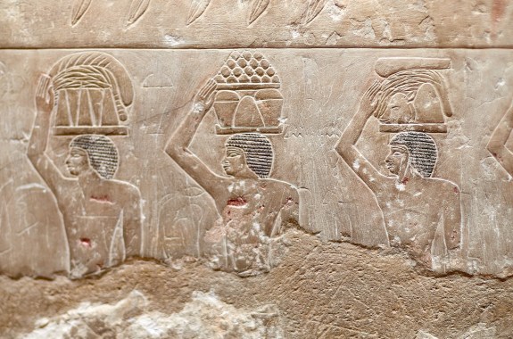 Saqqara, Egypt - 12102023: Procession of ancient Egyptian men carrying food offerings on their heads to the deceased owner of a V Dynasty mastaba - Idut. Saqqara, Egypt. Archaeology