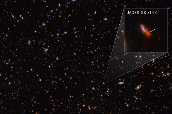 Faintly colored dots on a black sky, with an inset box showing a blurry reddish form like a short diagonal line.